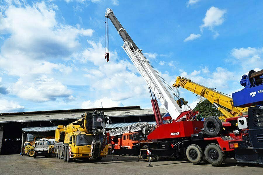 A red telescopic crane at Guzent's equipment yard.