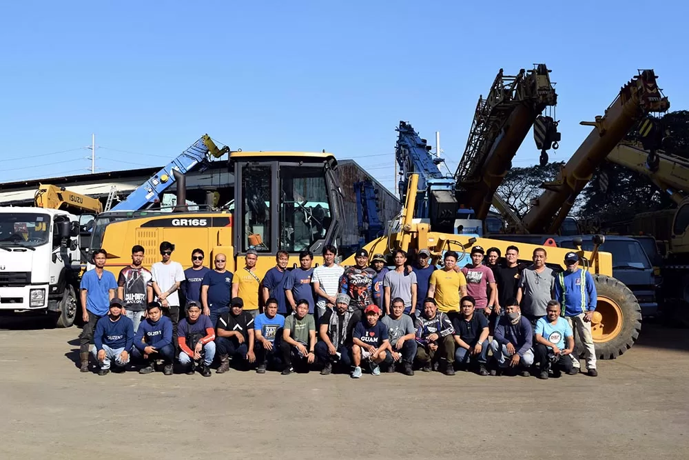 The Guzent operators and mechanics posting in front of a grader for a staff photo.